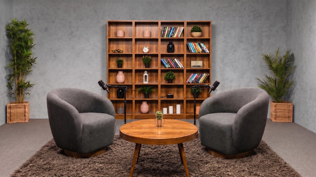 Brand grey podcast studio with grey armchairs, wooden bookshelf, and professional microphones at Winterfox Studios