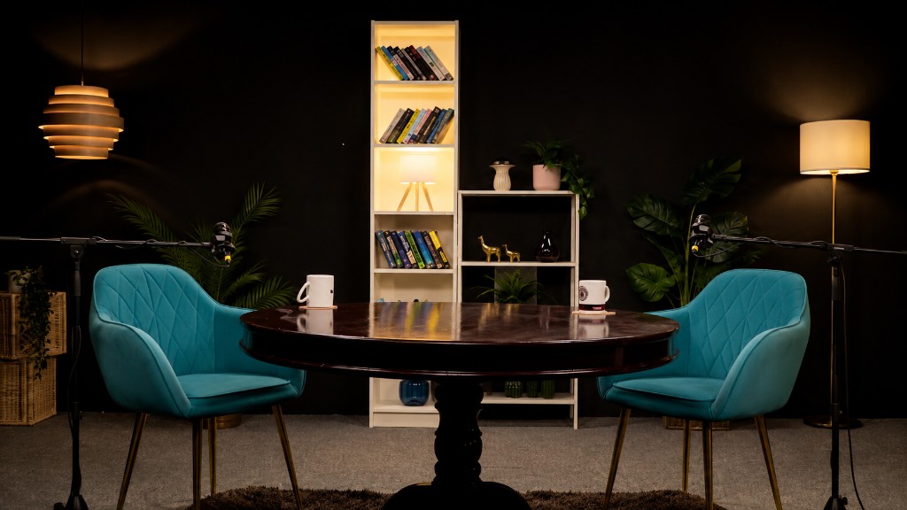 Round table podcast studio with teal velvet armchairs, dark wood pedestal table, and professional microphones at Winterfox Studios